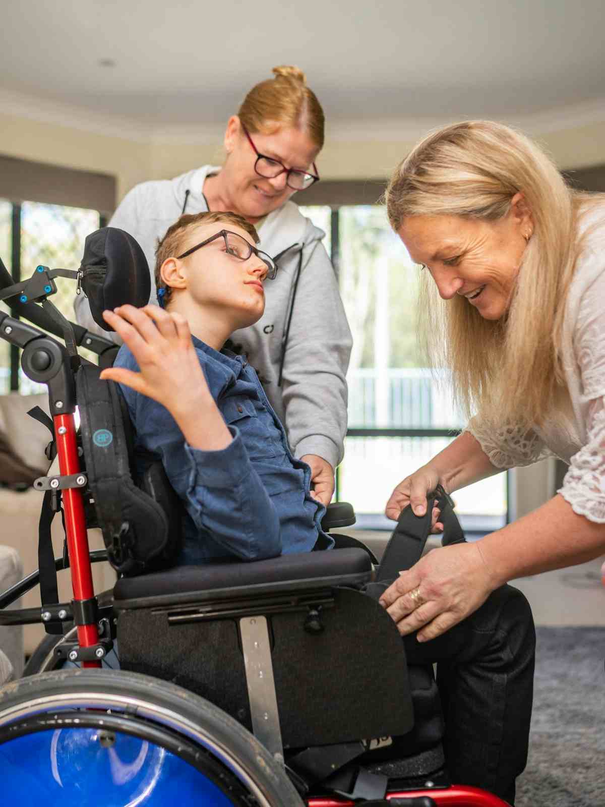 Daniels mother and friend supporting Daniel into his wheelchair